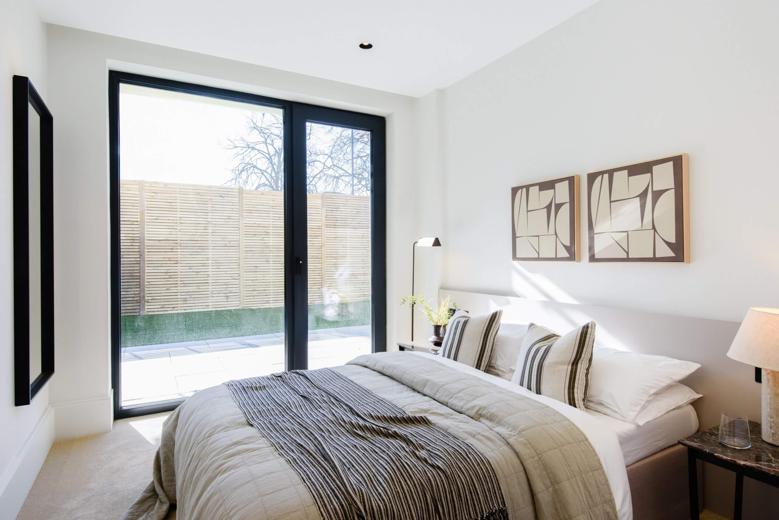 Modern bedroom with floor-to-ceiling glass doors opening to patio at Artscene, East Acton Lane, London W3 – Haus Properties